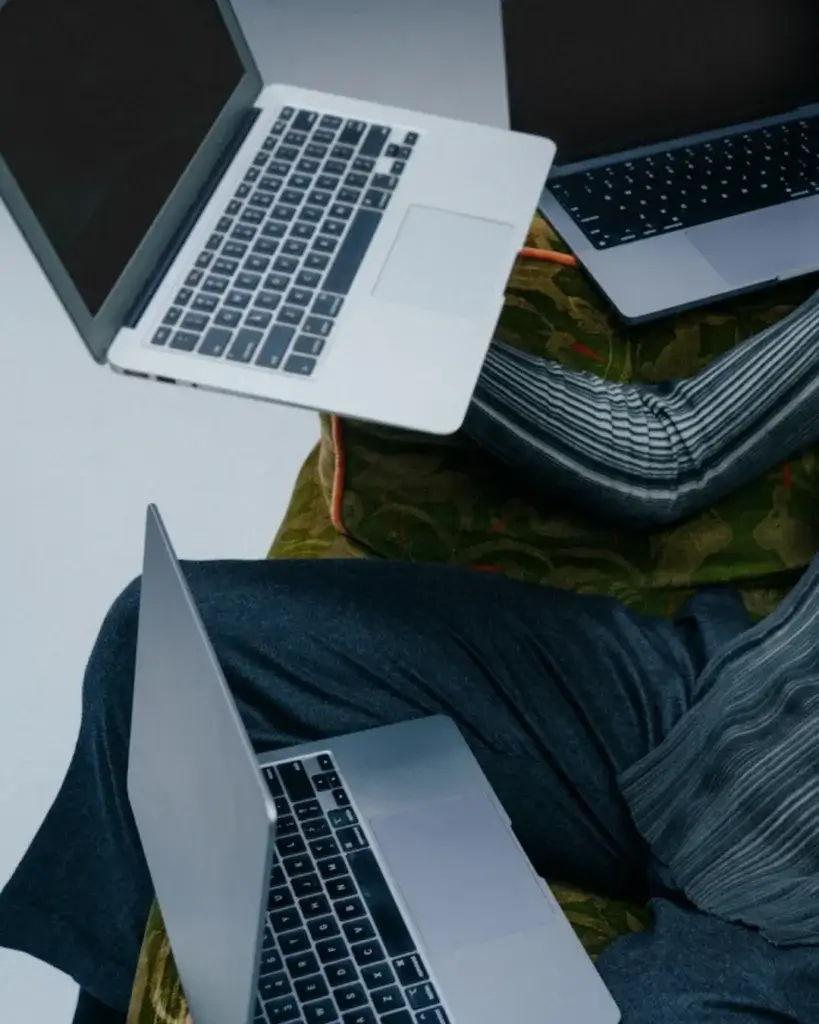 Overvældet selvstændig i kamp med tre laptops – et kaotisk billede på, hvorfor din WordPress hjemmeside skal være enkel, overskuelig og til at styre selv.